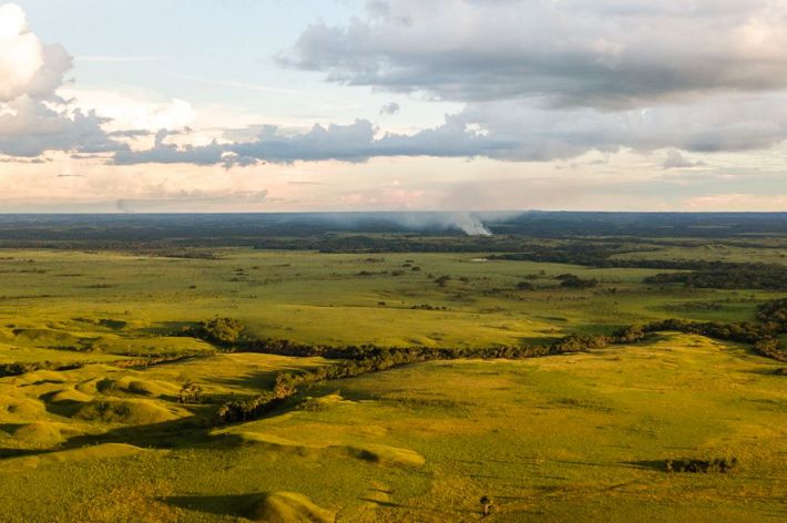 Smoke billowing in the distance on a grassland.