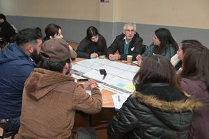  Un grupo diverso de personas participó en una discusión centrada alrededor de una mesa con papeles, una taza de café y un teléfono inteligente, en un entorno colaborativo.