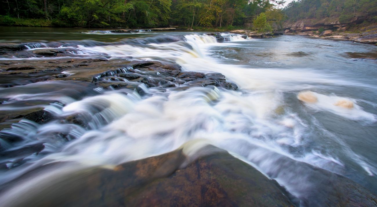 Rough river waters flow over rocks.