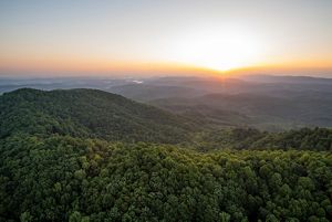 sunrise over a forested mountain range.