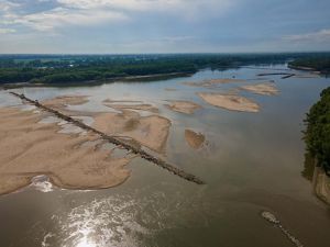 Aerial view of a rock jetty spanning the width of the muddy Mississippi River.