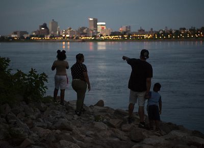 A family of four stands on banks of the Mississippi River to view a sunset over Memphis, Tennessee.
