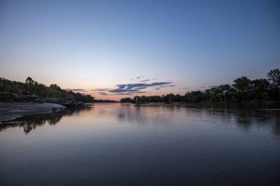 View of a wide, still river at sunset.