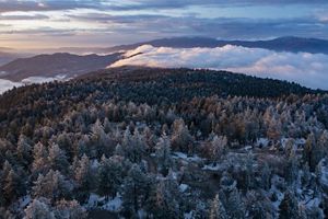 Clouds pour over the snow-covered Bear Mountain as the sun rises in Tehachapi, California United States.  