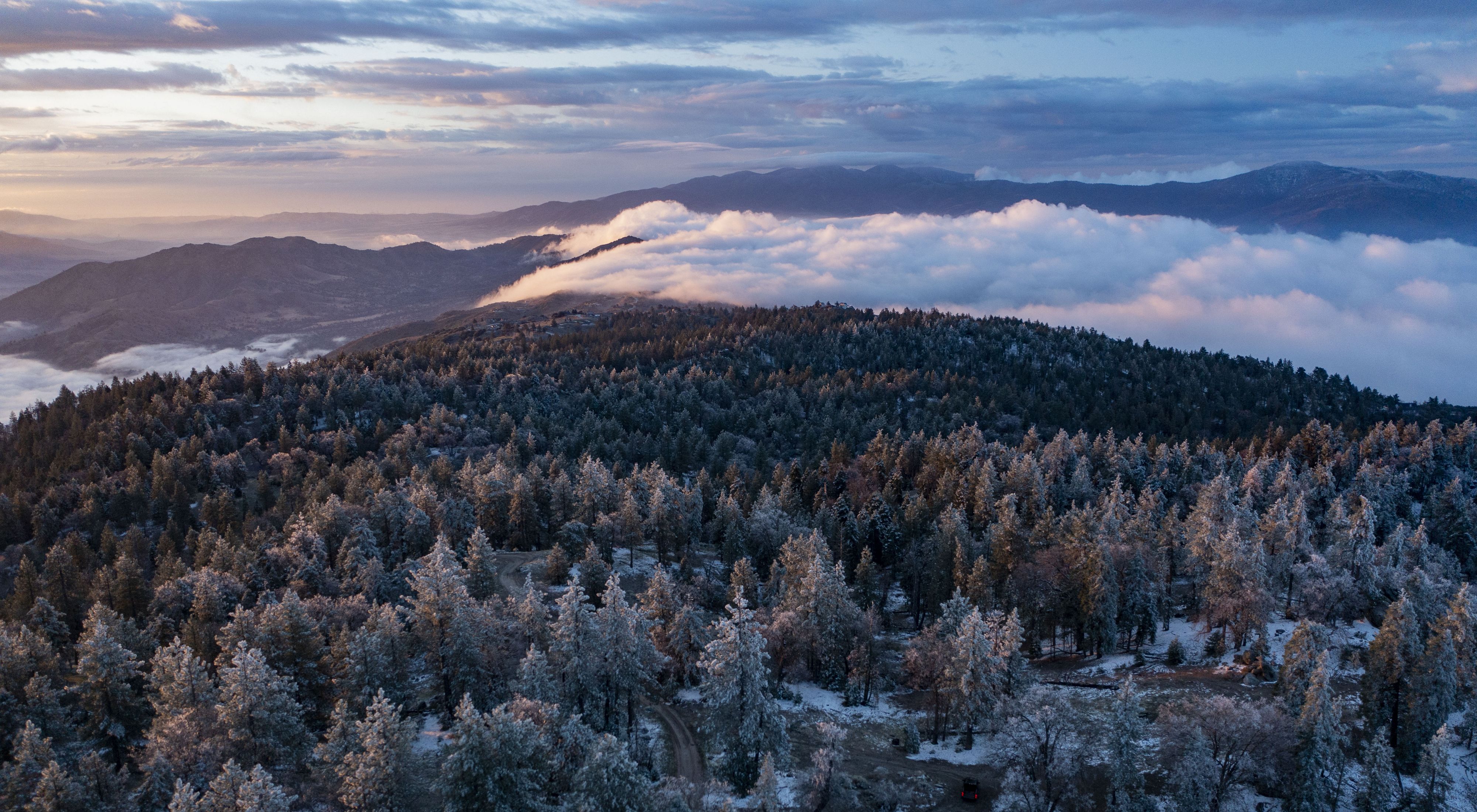 Clouds pour over the snow-covered Bear Mountain as the sun rises in Tehachapi, California United States.  