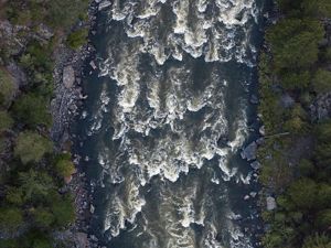 Aeriel view of river water running over rocks with dark lighting.