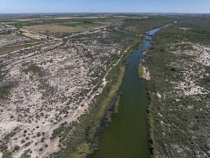 Aerial view of a river cuttings through a green area with dry spots.
