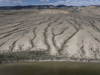 Aerial view of a mountains in the distance and a dry river landscape in the middle and foreground.