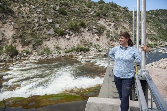 A person stands on a concrete structure above a rushing river.