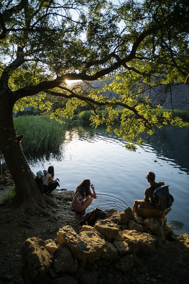 Hikers rest on a riverbank.