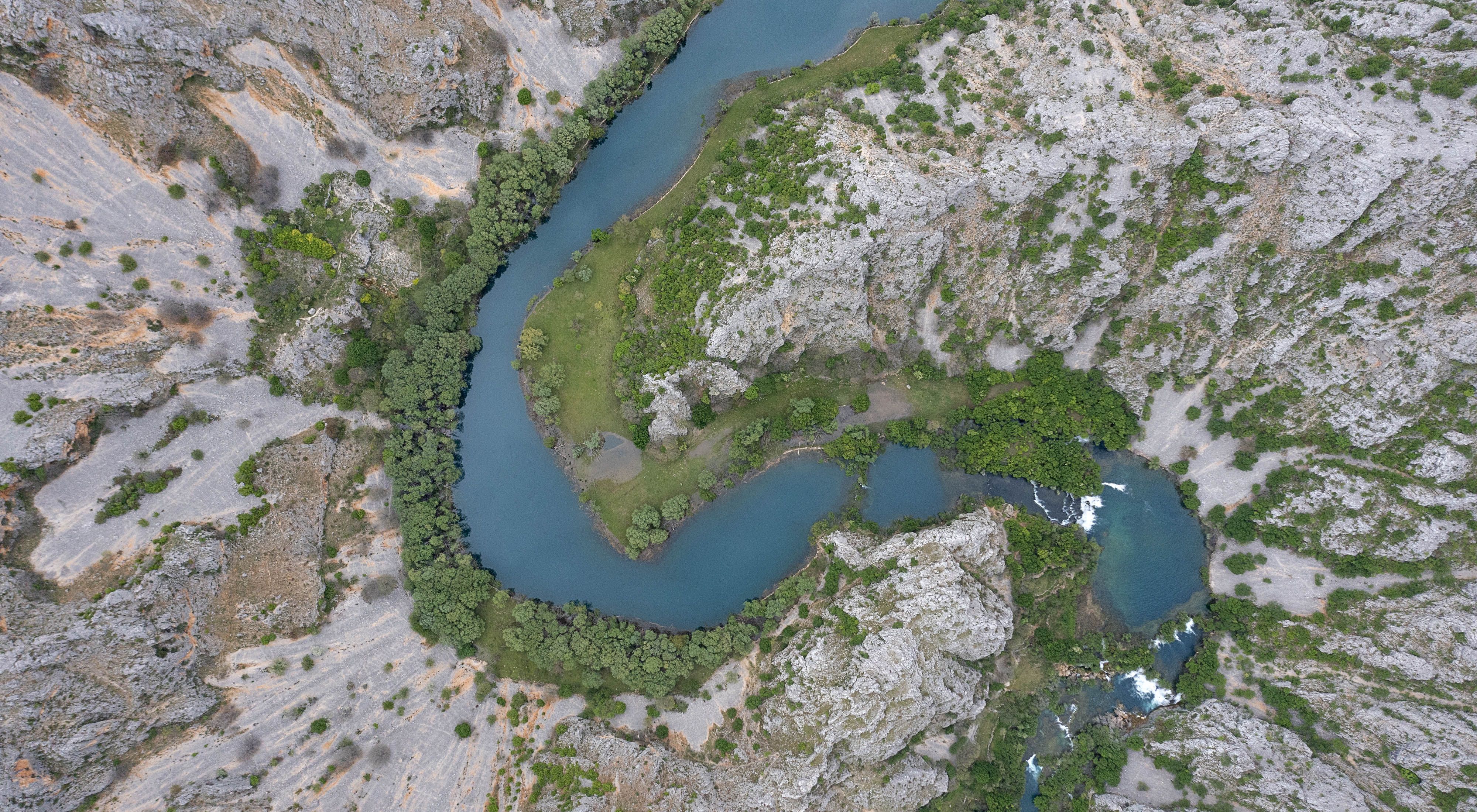 Aerial view looking straight down on a river that winds in an S curve through rocky terrain.