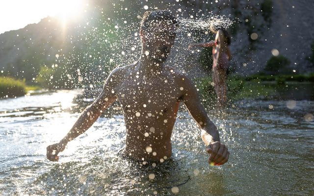 A person splashes water while swimming in the Krupa River.