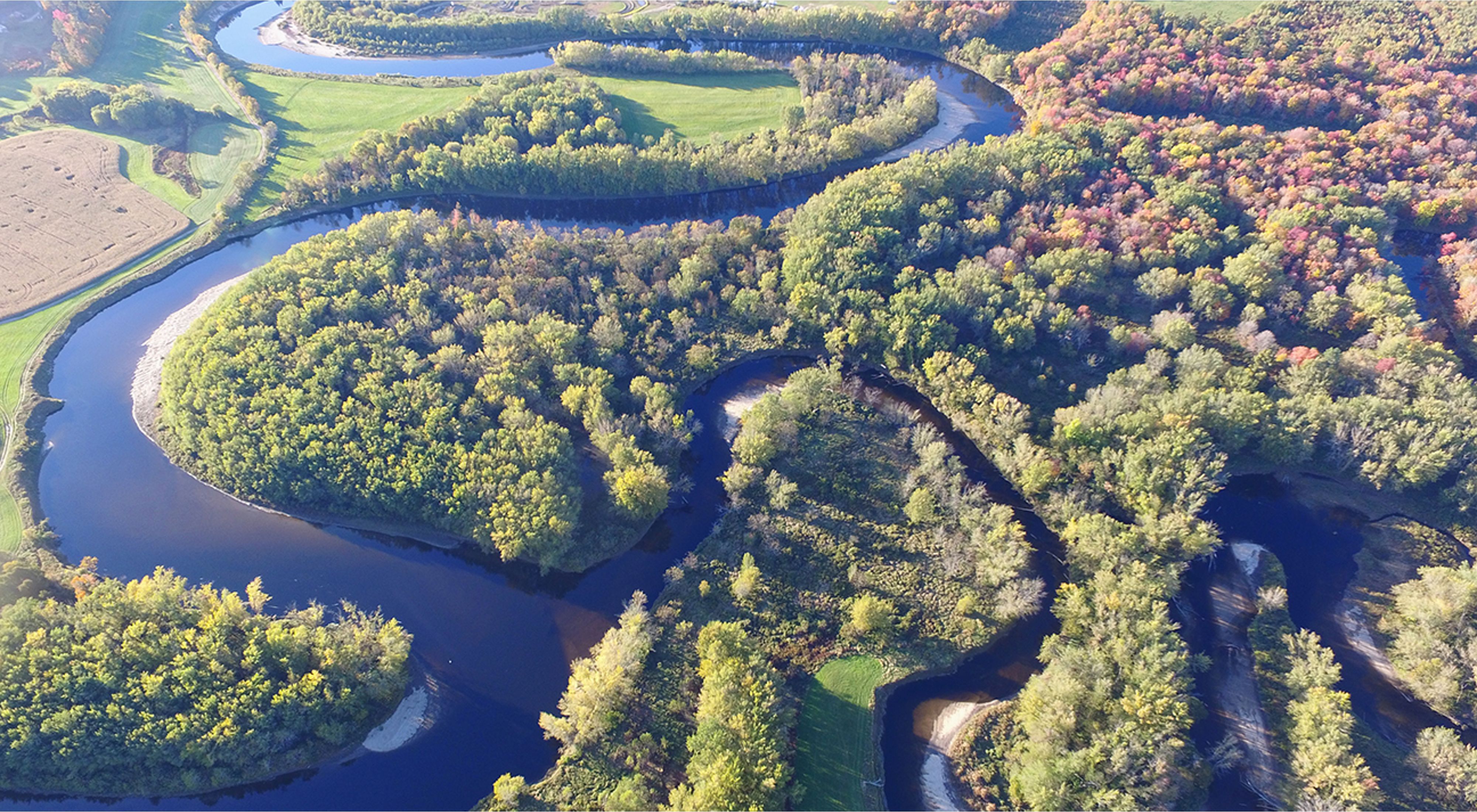 An aerial view of a river winding through a forested landscape.