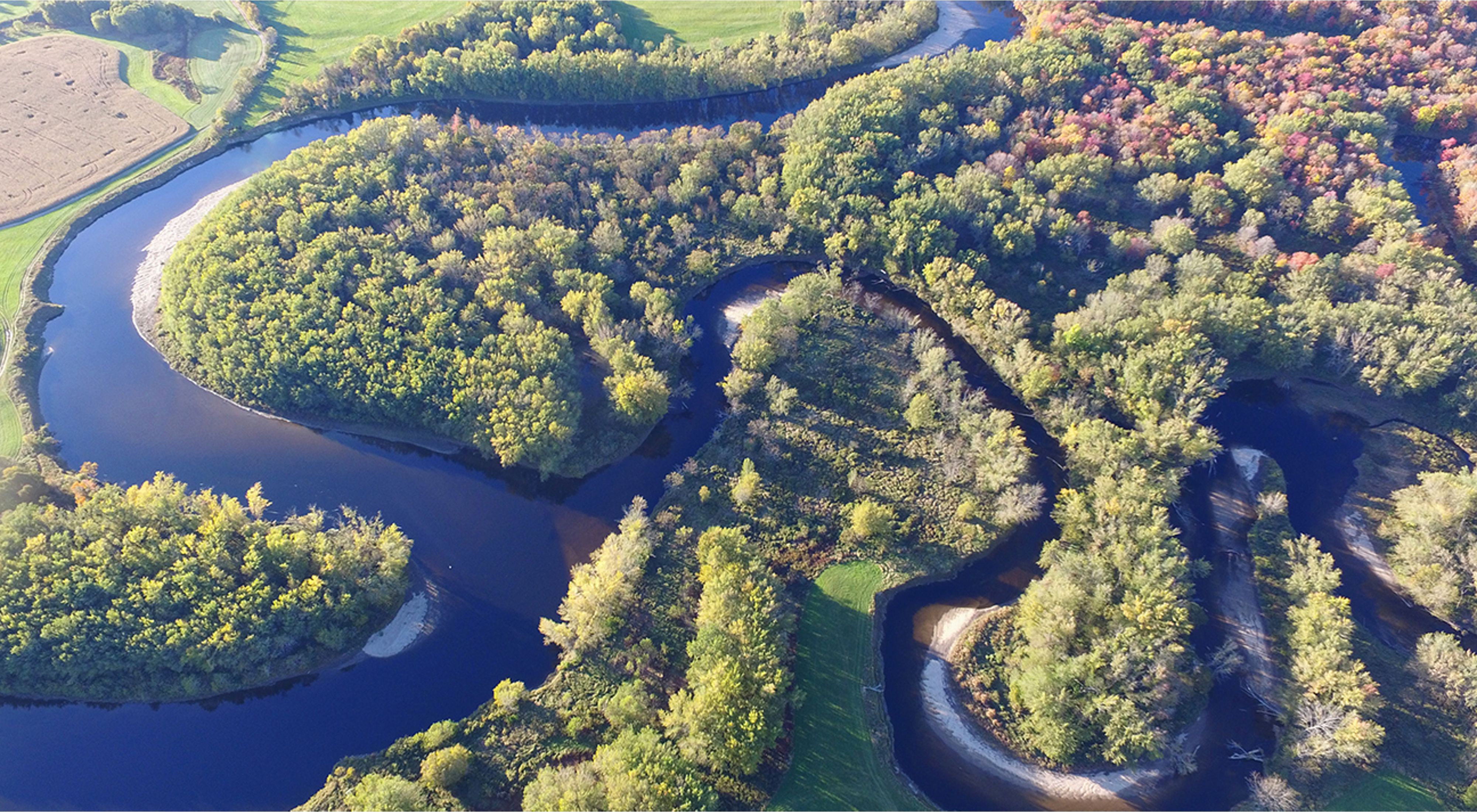 An aerial view of a river winding through a forested landscape.