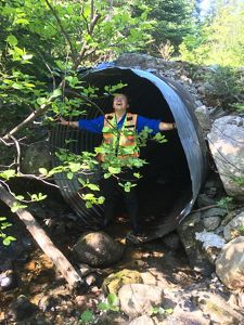 Hadley Couraud stands triumphantly in a culvert while conducting field research.