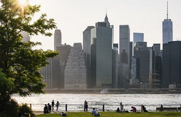 A view across a body of water of a dense group of tall city buildings.