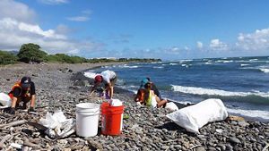 People picking up trash on a beach. 