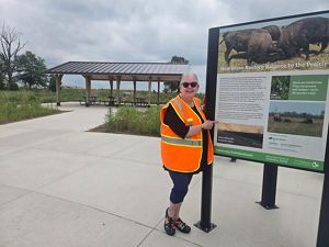 Bison Ranger Mary Kay Emmrich stands next to a sign at the Bison Viewing Center.