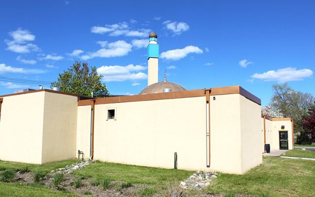Back of the tan-painted Masjid An-Nur mosque building with bioswale (rain garden) in the foreground.