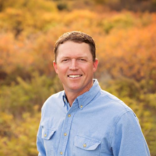 Matt Bain, a man in a blue shirt, stands outdoors and smiles.