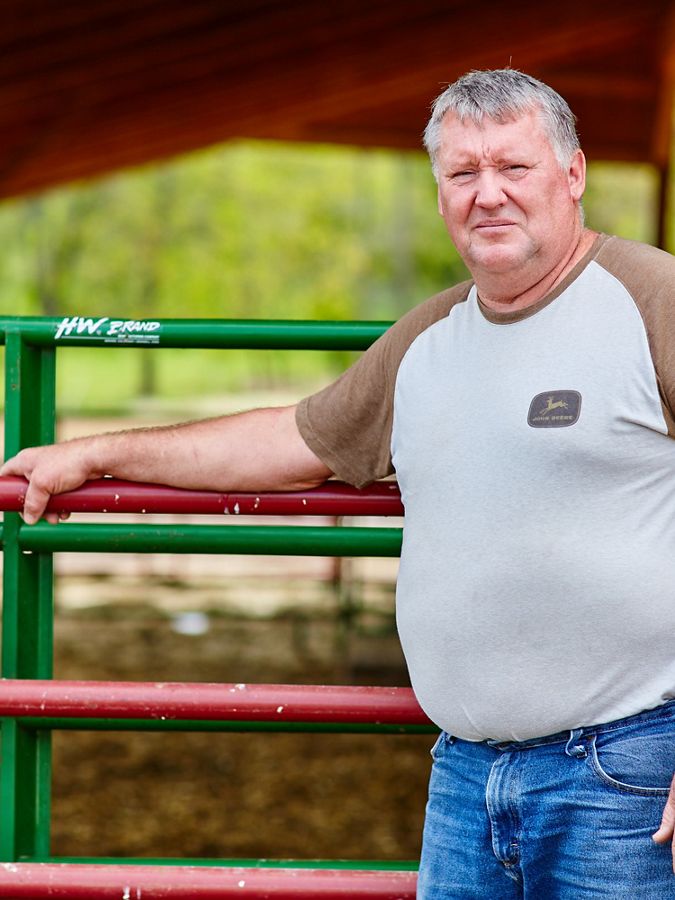 Farmer standing in front of a gate.