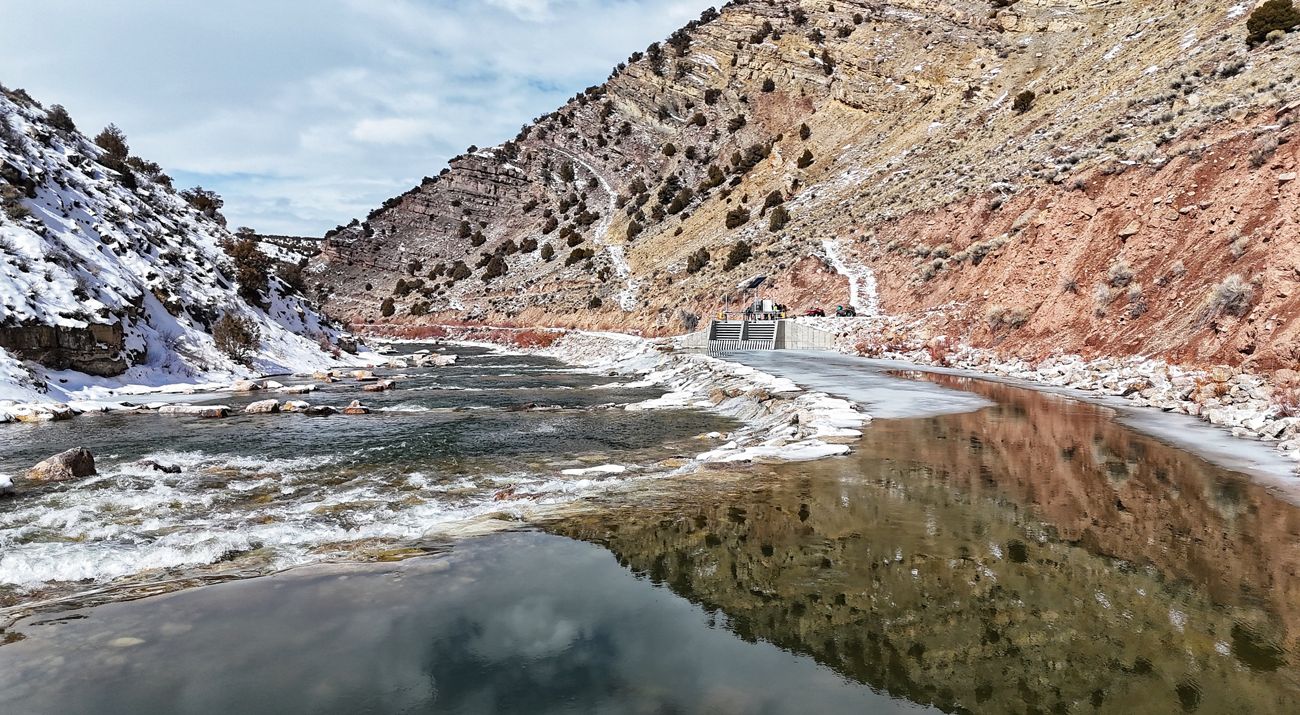 A river flowing through a valley with snow on the side banks.