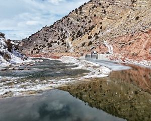 A river flowing through a valley with snow on the side banks.