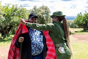 A woman places a red blanket on the shoulders of a man.