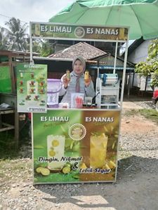 A woman holds up pineapple-based products made from her farm at a small stand.