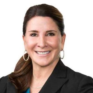 A woman wearing a dark suit smiles at the camera.