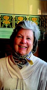 A woman wearing a colorful scarf smiles at the camera.