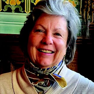 A woman with a colorful scarf around her neck smiles.