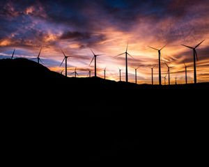 Wind turbines silhouetted against the sky at sunset.