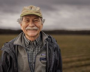 two workers with shovels and gear in a field.