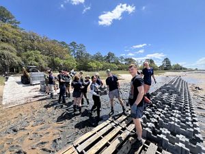 Volunteers work together along an assembly line, passing heavy concrete Oyster Castle pieces to the living shoreline site. 