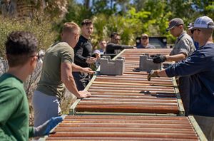 Three men move concrete blocks down a  table. 
