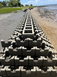 Concrete blocks interlock to create a wall, dividing ocean and shoreline.