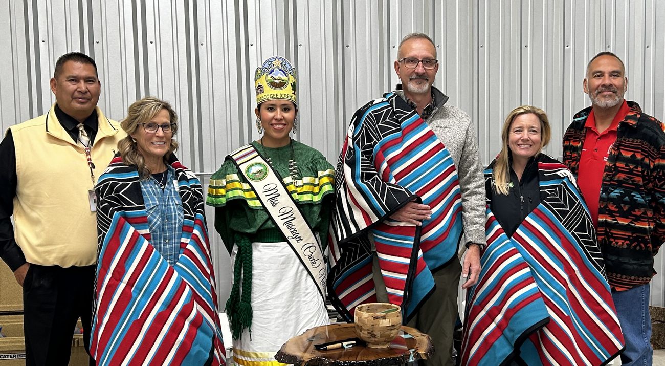 Three men and three women stand together following an exchange of ceremonial gifts.