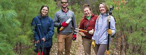 Four staff members pose on a trail with tools.