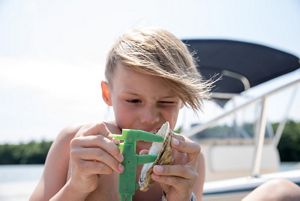 A young boy measures a baby oyster with green calipers.