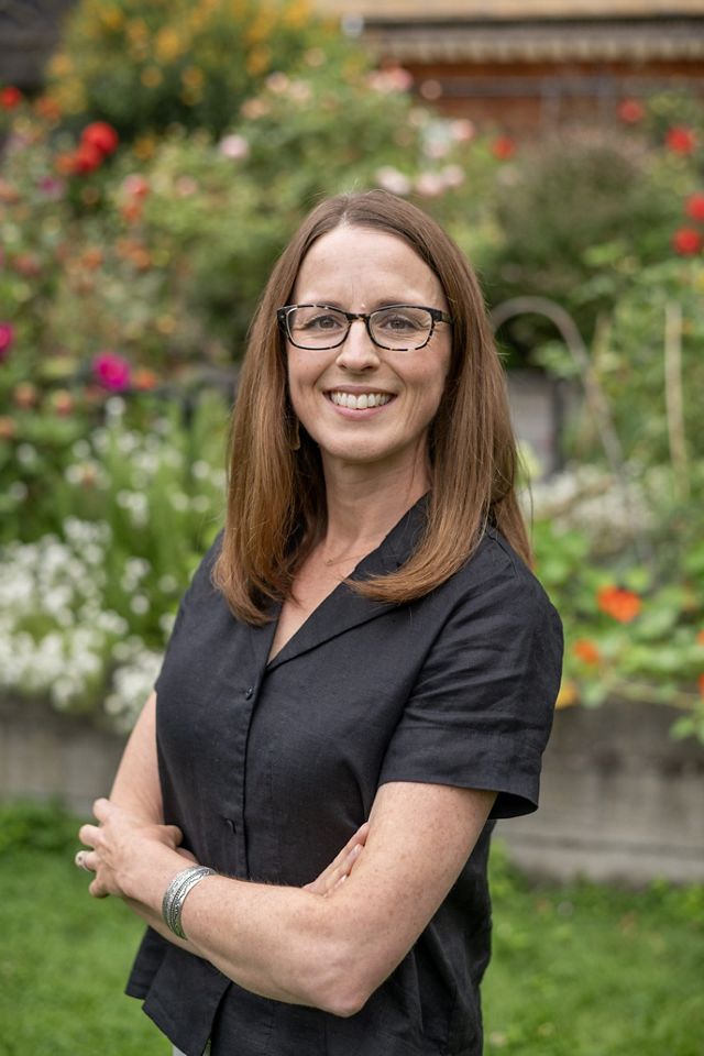 A woman stands in front of flowers. 