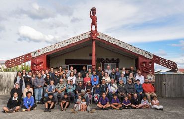 A group of people sitting in front of a building with red embellishments.