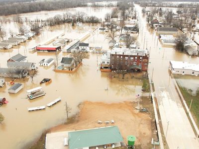 An aerial photo of a small community with multiple buildings and roads underwater due to a flood.