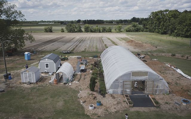 Aerial image of farm with high tunnel and other builds.