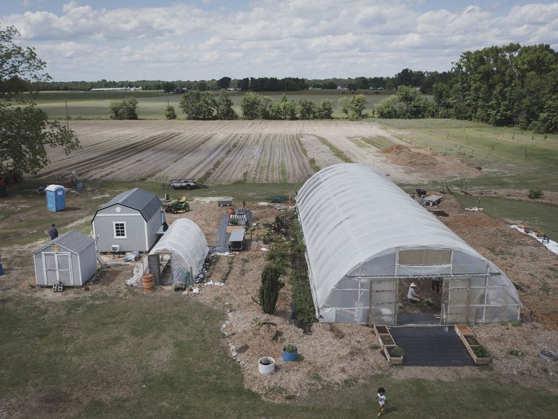 Aerial image of farm with high tunnel and other builds.