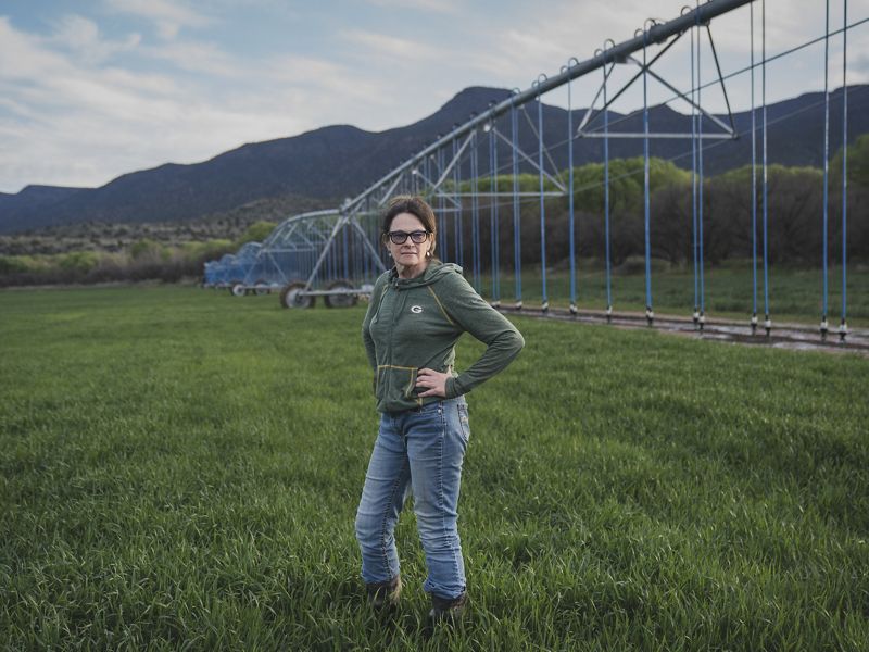 Mujer en sus campos de cultivo y sistemas de riego.