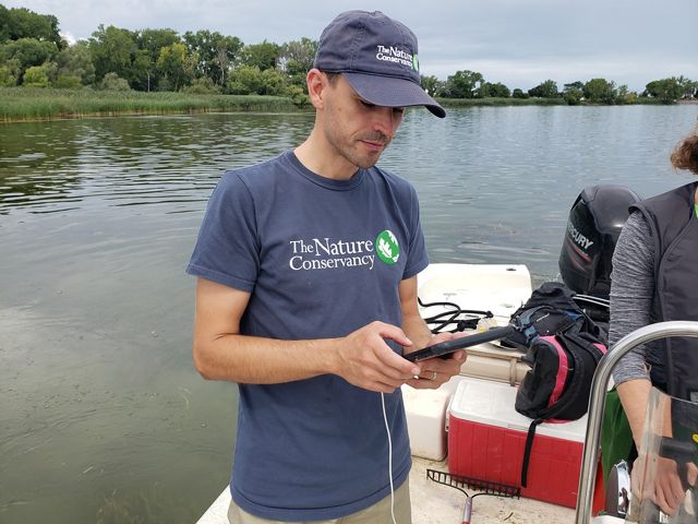 Andrew Tucker of TNC holds an electronic device and records information from the field.   