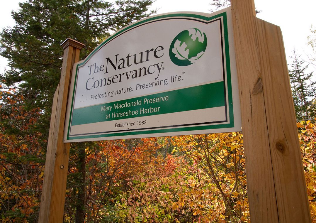 Mary Macdonald Preserve signage in front of autumn-colored trees. The preserve is located in the Keweenaw Peninsula in Michigan's Upper Peninsula. 