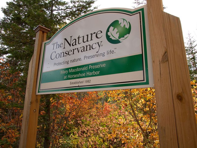Mary Macdonald Preserve signage in front of autumn-colored trees. The preserve is located in the Keweenaw Peninsula in Michigan's Upper Peninsula.