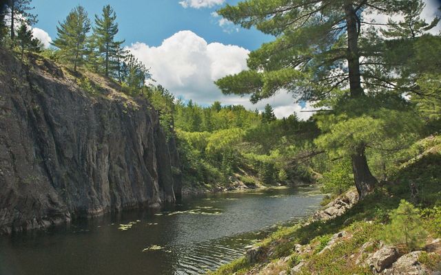 A river runs along a tall outcropping at Echo Lake Preserve in Marquette, Michigan before turning and disappearing around the bend. 